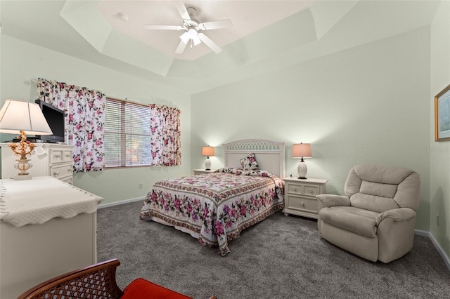 bedroom with a raised ceiling, ceiling fan, and dark carpet