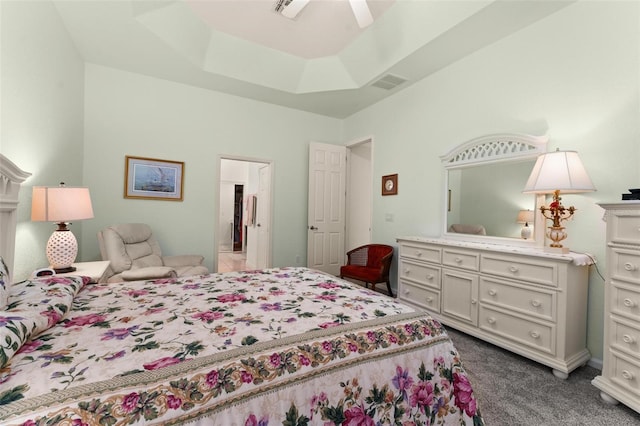 carpeted bedroom with ceiling fan and a tray ceiling