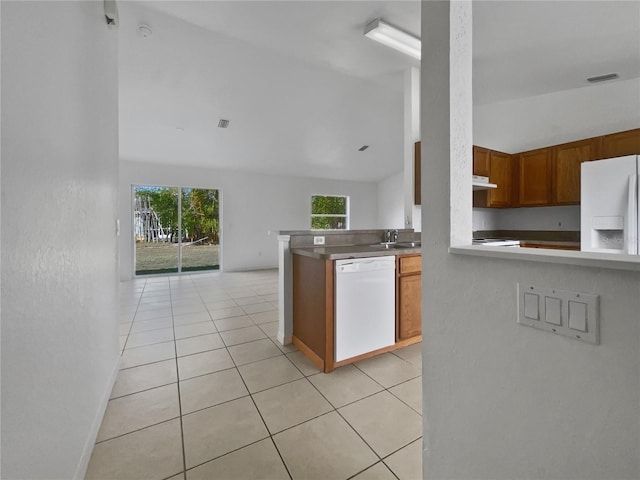 kitchen with sink, lofted ceiling, white appliances, light tile patterned floors, and kitchen peninsula