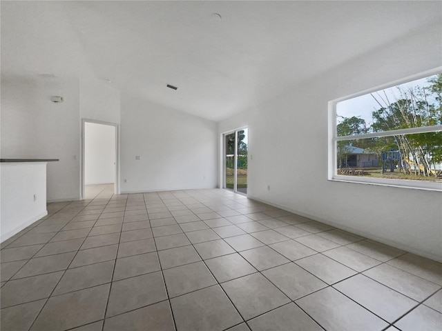 empty room featuring vaulted ceiling and light tile patterned floors