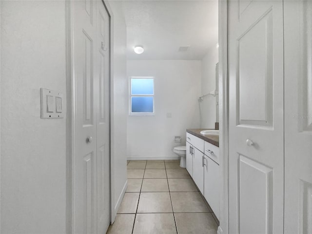 bathroom with toilet, vanity, and tile patterned flooring