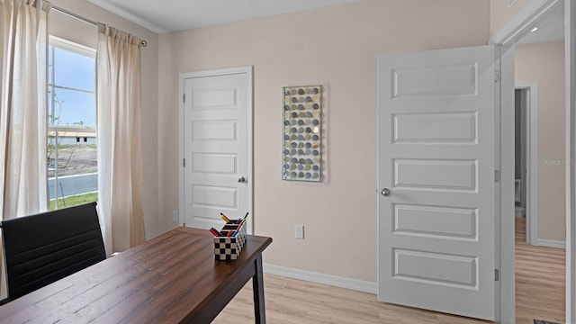 home office with light hardwood / wood-style floors and a wealth of natural light