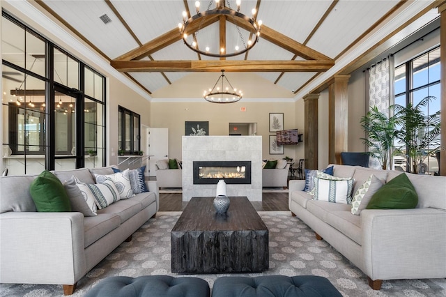 living room with a tiled fireplace, beam ceiling, a chandelier, and high vaulted ceiling