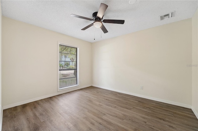 unfurnished room featuring baseboards, a textured ceiling, visible vents, and wood finished floors