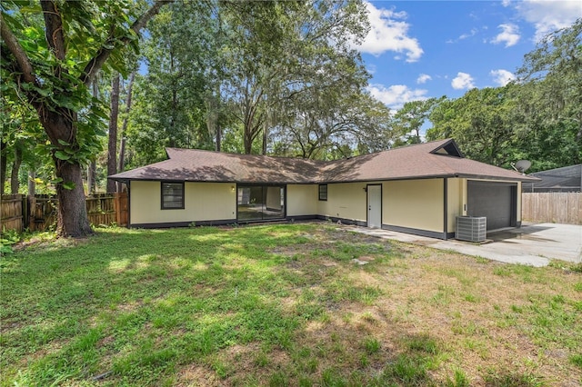 ranch-style home featuring cooling unit, a front lawn, and a garage