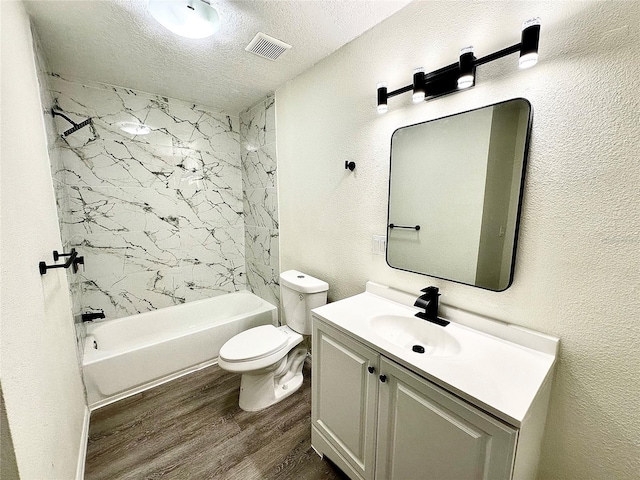 bathroom featuring a textured ceiling, toilet, wood finished floors, vanity, and visible vents