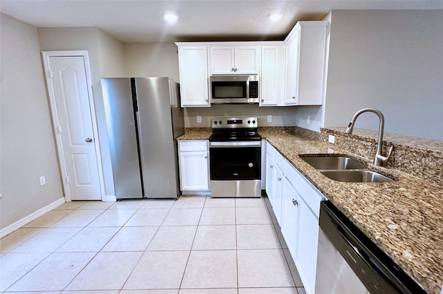 kitchen with white cabinetry, sink, dark stone counters, light tile patterned floors, and stainless steel appliances