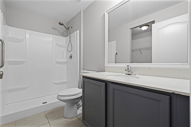 bathroom featuring vanity, a textured ceiling, a shower, tile patterned floors, and toilet