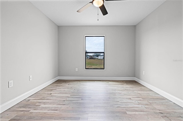 empty room with ceiling fan and light hardwood / wood-style flooring