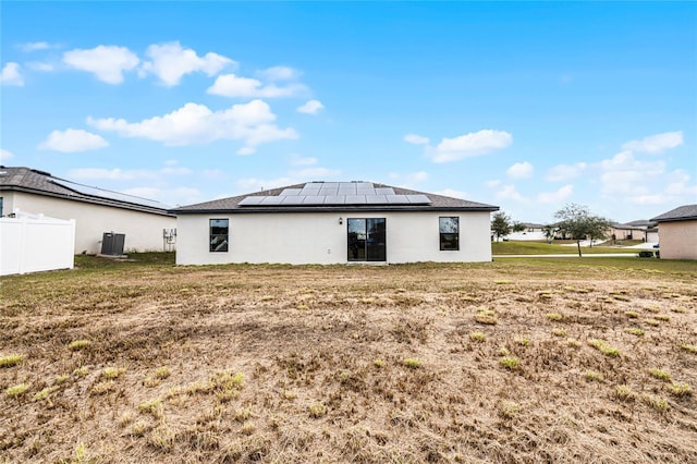 rear view of property with a lawn, solar panels, and central air condition unit