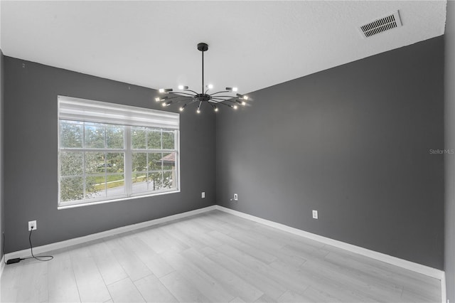 unfurnished room with light wood-type flooring and a chandelier