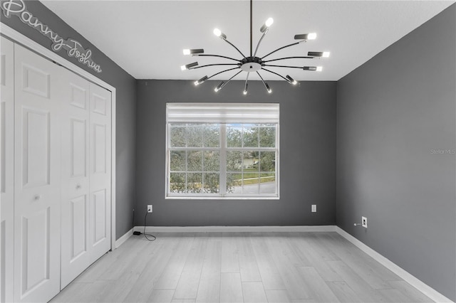 unfurnished bedroom featuring a closet, a notable chandelier, and light hardwood / wood-style flooring