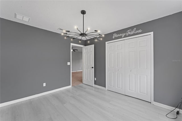 unfurnished bedroom with a notable chandelier, a closet, and light hardwood / wood-style flooring