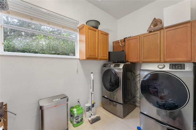 laundry room featuring washer and dryer, cabinets, and light tile patterned floors