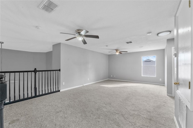 carpeted spare room with a textured ceiling and ceiling fan