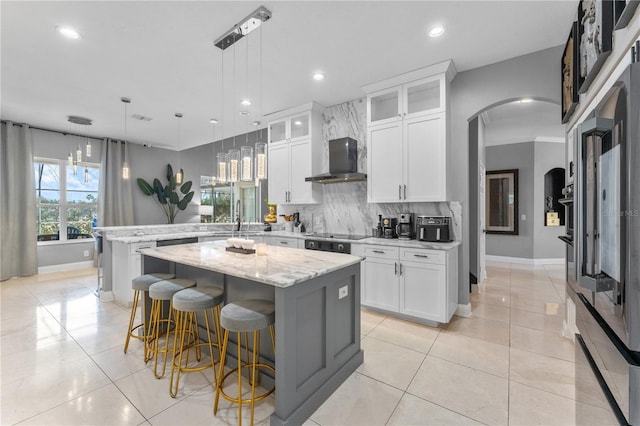 kitchen featuring a center island, white cabinetry, light stone counters, light tile patterned floors, and hanging light fixtures