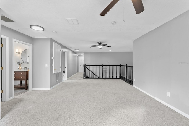 empty room with light carpet, visible vents, baseboards, and a ceiling fan