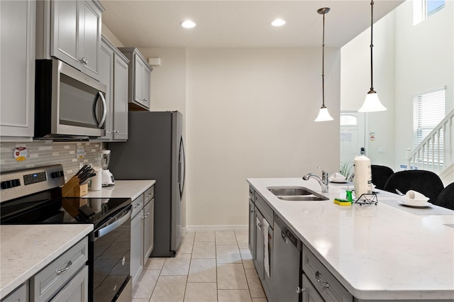 kitchen with sink, gray cabinetry, hanging light fixtures, and appliances with stainless steel finishes