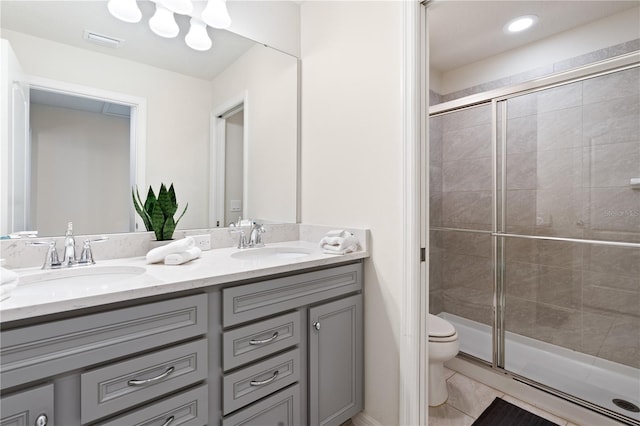 bathroom with vanity, toilet, tile patterned floors, and a shower with shower door