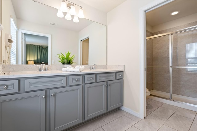 bathroom with a shower with door, toilet, vanity, and tile patterned flooring