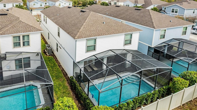 back of property with a swimming pool with hot tub, a lanai, and central air condition unit