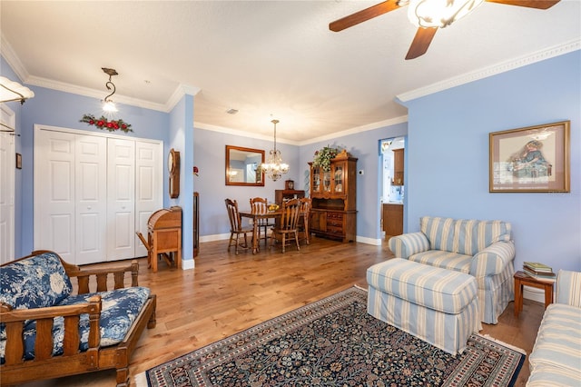 living room featuring crown molding, ceiling fan with notable chandelier, and light hardwood / wood-style flooring