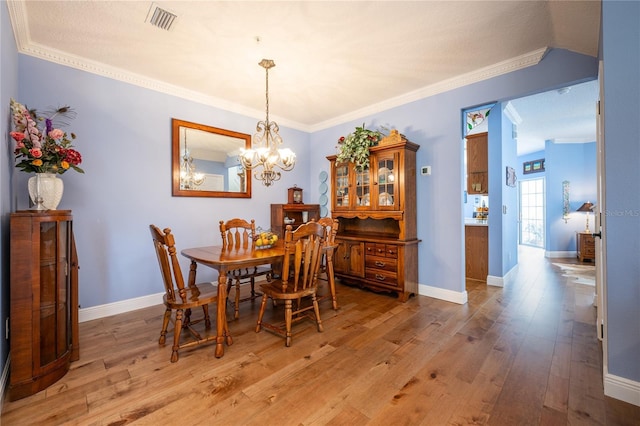 dining room featuring wood-type flooring, ornamental molding, and a notable chandelier