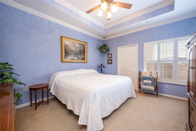 carpeted bedroom with ceiling fan, ornamental molding, a raised ceiling, and a closet