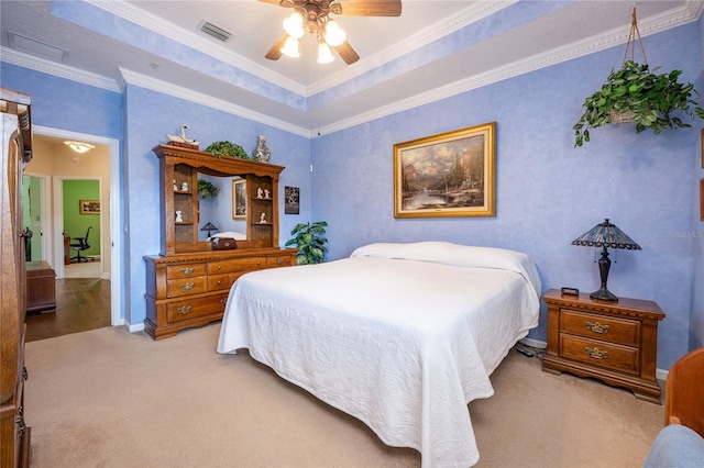 bedroom with light carpet, a tray ceiling, ornamental molding, and ceiling fan