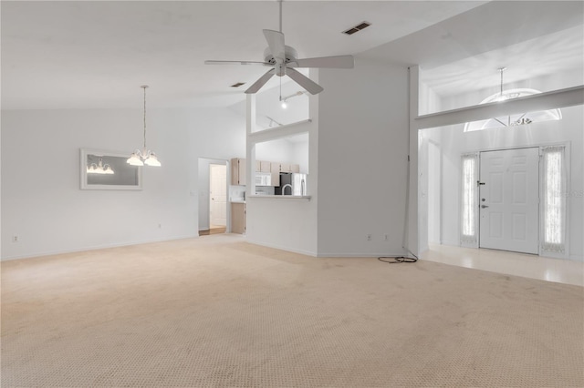 unfurnished living room featuring carpet, ceiling fan with notable chandelier, and high vaulted ceiling