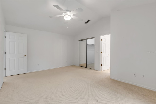 unfurnished bedroom featuring ceiling fan, lofted ceiling, a closet, and light carpet