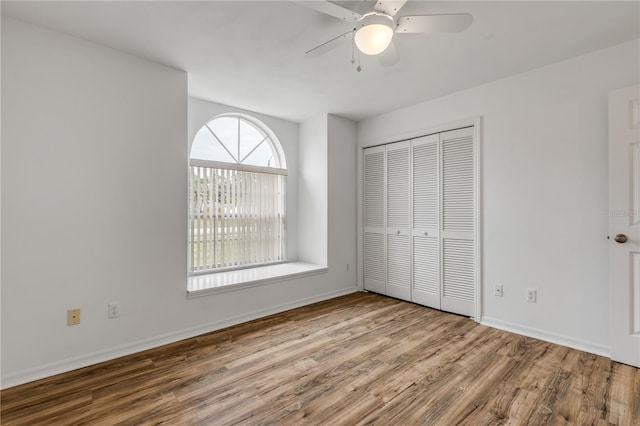 unfurnished bedroom featuring hardwood / wood-style floors, a closet, and ceiling fan