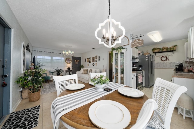 dining space with a textured ceiling, light tile patterned floors, and a notable chandelier