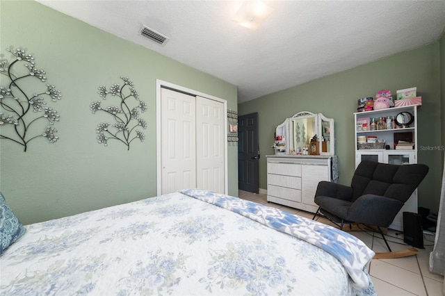 tiled bedroom featuring a textured ceiling and a closet