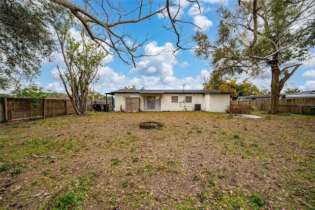 rear view of house with central air condition unit and a yard