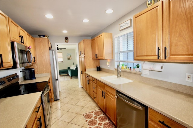 kitchen featuring appliances with stainless steel finishes, sink, light tile patterned floors, and ceiling fan