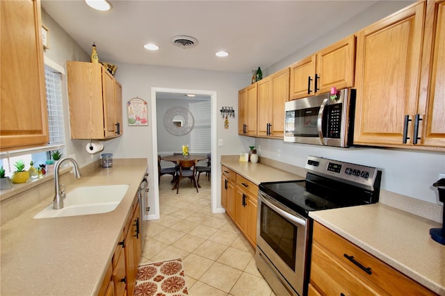 kitchen with light tile patterned flooring, appliances with stainless steel finishes, sink, and light brown cabinets