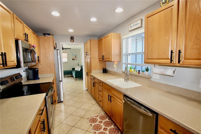 kitchen with stainless steel appliances, sink, light tile patterned floors, and ceiling fan