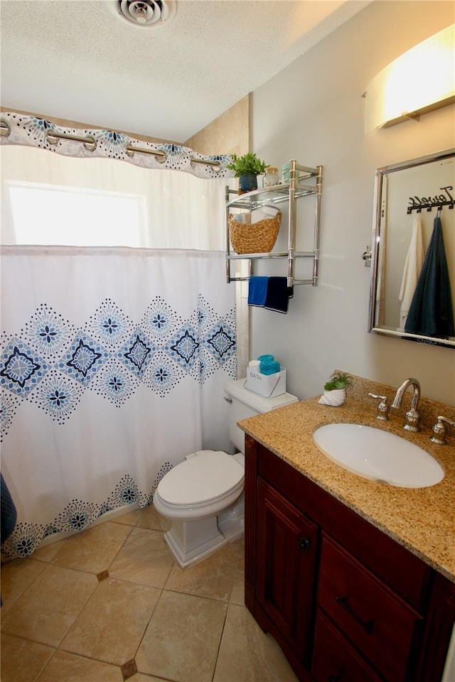 bathroom featuring vanity, tile patterned floors, a textured ceiling, and toilet