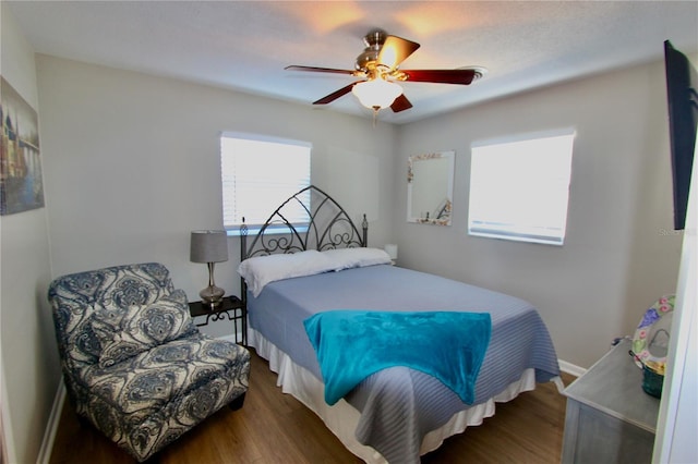 bedroom featuring dark wood-type flooring, ceiling fan, and multiple windows