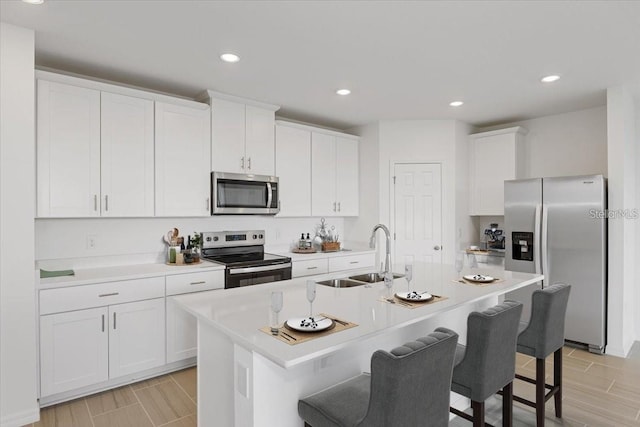 kitchen featuring sink, stainless steel appliances, a breakfast bar, and a kitchen island with sink