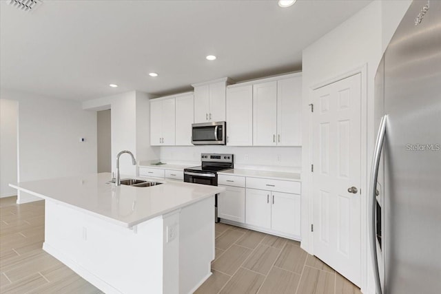 kitchen featuring stainless steel appliances, an island with sink, white cabinets, a kitchen breakfast bar, and sink