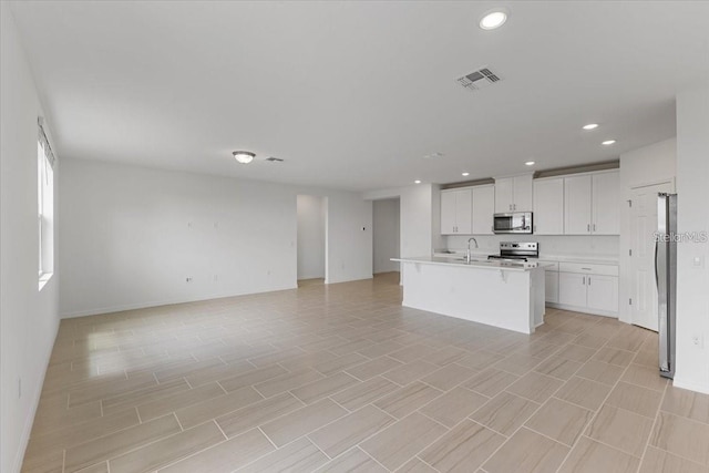 kitchen with sink, stainless steel appliances, white cabinetry, and a kitchen island with sink