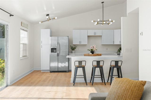 kitchen featuring lofted ceiling, white cabinets, stainless steel fridge with ice dispenser, and an inviting chandelier