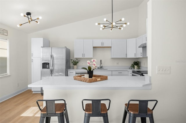 kitchen with white cabinetry, appliances with stainless steel finishes, kitchen peninsula, and a breakfast bar area