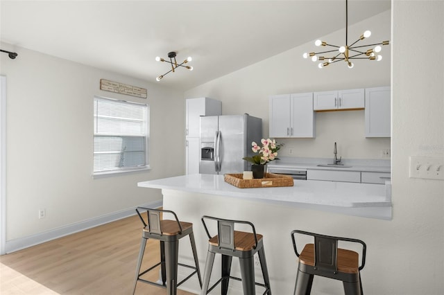 kitchen with an inviting chandelier, white cabinetry, light hardwood / wood-style floors, stainless steel refrigerator with ice dispenser, and sink