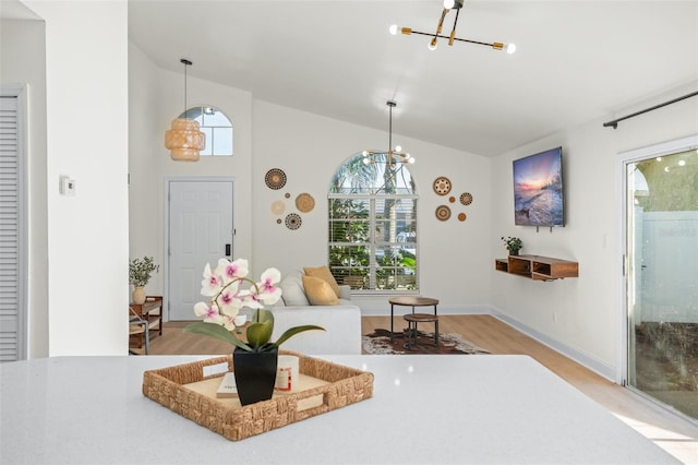 living room featuring light hardwood / wood-style floors, lofted ceiling, and a chandelier