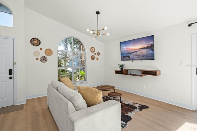 living room featuring an inviting chandelier, lofted ceiling, and light hardwood / wood-style floors