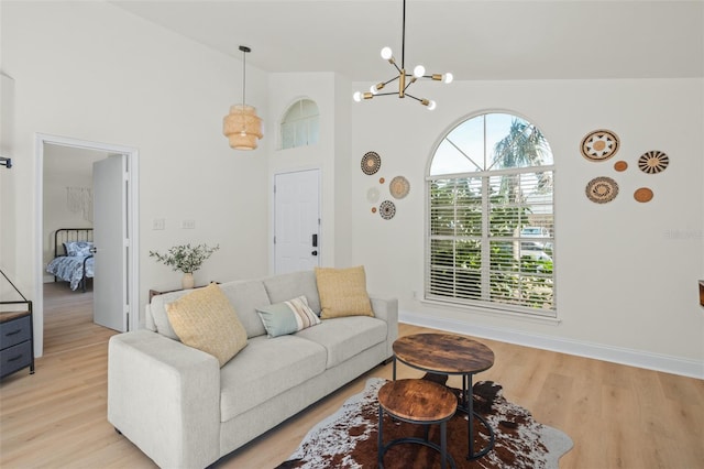 living room with an inviting chandelier, light hardwood / wood-style flooring, and high vaulted ceiling