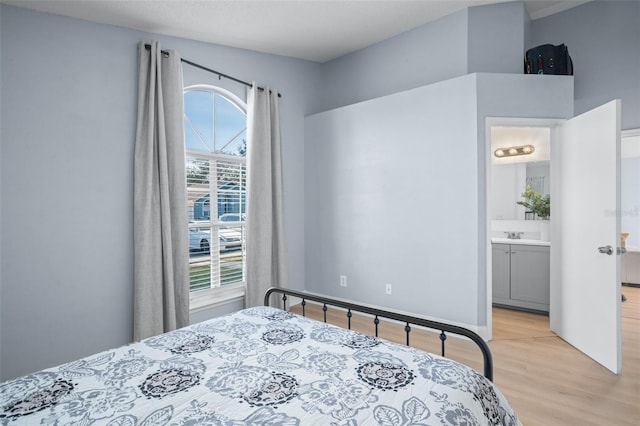 bedroom with light hardwood / wood-style floors, multiple windows, and ensuite bathroom